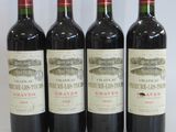 four bottles of wine are lined up on a white surface