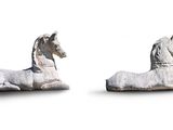 two statues of a horse and a horse laying on the ground