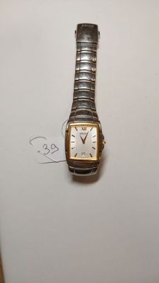 une image représentant une montre en argent et en or posée sur une surface blanche