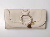 un sac à main en cuir beige orné d'un anneau doré et d'un porte-clés, posé sur une table blanche