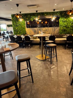 tables and stools in a restaurant with plants growing on the walls