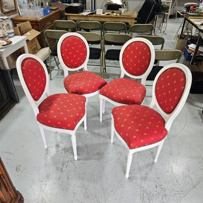 four red and white chairs in a room with many other chairs