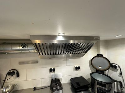 une cuisine équipée d'une cuisinière, d'une plaque de cuisson et d'une hotte aspirante