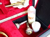 a red case with a trumpet and a bottle of liquid in it