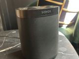 a black speaker sitting on top of a table next to a chair