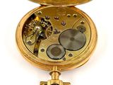 a gold pocket watch that is open on a white surface