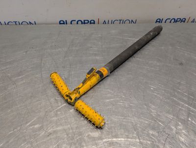 a close up of a metal object on a table with a yellow handle
