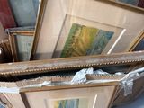 une pile d'œuvres d'art encadrées posées par terre dans une pièce