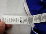 a person holding a white and blue shirt with a label on it
