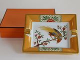 un petit plateau sur lequel se trouve un oiseau, avec une boîte orange derrière