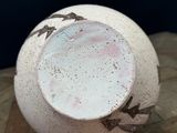 a white vase with birds on it sitting on a wooden table