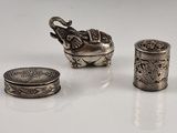 trois objets en argent posés les uns à côté des autres sur une table