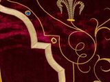 a close up of a red and gold blanket with gold trimming