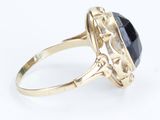 a close up of a gold ring with a black stone
