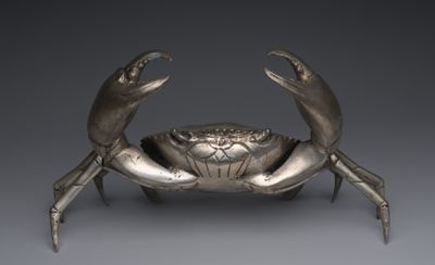 une image représentant une statue de crabe argentée sur fond gris
