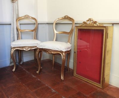 deux chaises dorées et une porte rouge dans une pièce