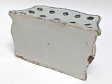 a white and blue vase that has holes in it