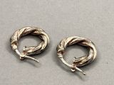 two pairs of silver earrings with twisted wire on a gray surface