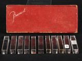 six cassettes are lined up in a red case on a black surface