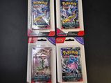 four packs of pokemon trading cards on a black table