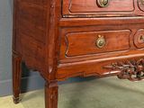 a small wooden chest of drawers on a green carpet