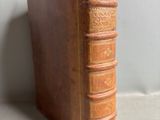 un vieux livre marron posé sur une table blanche