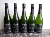 six bottles of champagne lined up on a table
