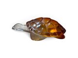 figurine de tortue en verre brun posée sur une surface blanche