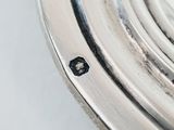 a close up view of a silver clock on a white surface