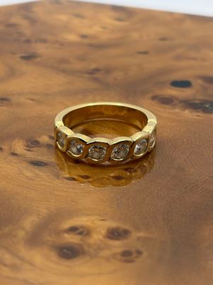 bague en or jaune sertie de diamants posée sur une surface en bois