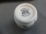 a close up of a small white vase on a table