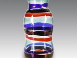 un vase en verre multicolore posé sur une surface blanche