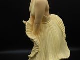figurine représentant une femme en robe jaune sur fond noir