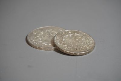 deux pièces d'argent posées l'une sur l'autre sur une surface blanche
