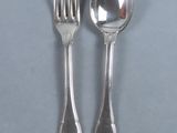 two silver spoons and a fork on a table