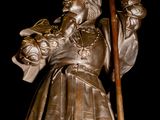 a bronze statue of a man holding a shovel and a bag