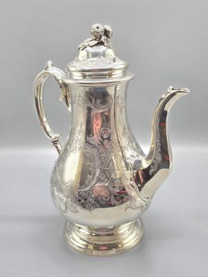 une théière ancienne en argent avec son couvercle, posée sur une table