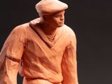 un gros plan sur une figurine en argile représentant un homme tenant un panier