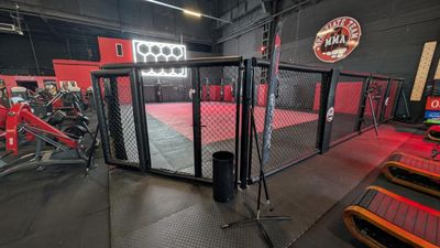 the inside of a gym with red and black walls and a cage