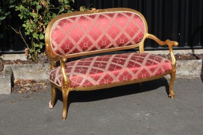 a red and gold couch sitting in the middle of a parking lot