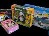 three boxes of legos sitting on a black surface