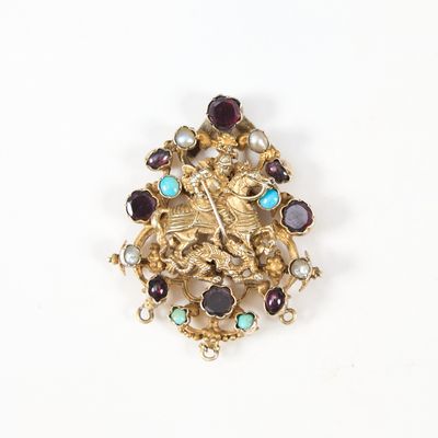 une broche ancienne en or, ornée de pierres de différentes couleurs sur un fond blanc