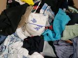 un carton rempli de vêtements et des vêtements par terre