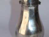 une salière en argent posée sur une surface blanche