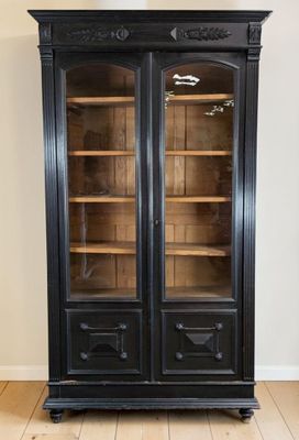 an antique black bookcase with glass doors in a living room
