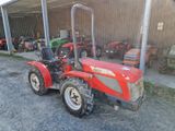 un tracteur rouge garé devant un bâtiment