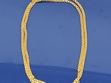 un gros plan d'un collier en or posé sur une surface bleue