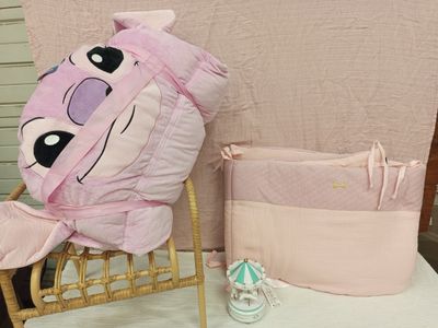 une peluche rose posée sur une chaise à côté d'un lit de bébé
