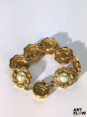 une image représentant un bracelet en or orné de perles sur un fond blanc