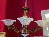 un lustre auquel sont suspendus trois abat-jours en verre